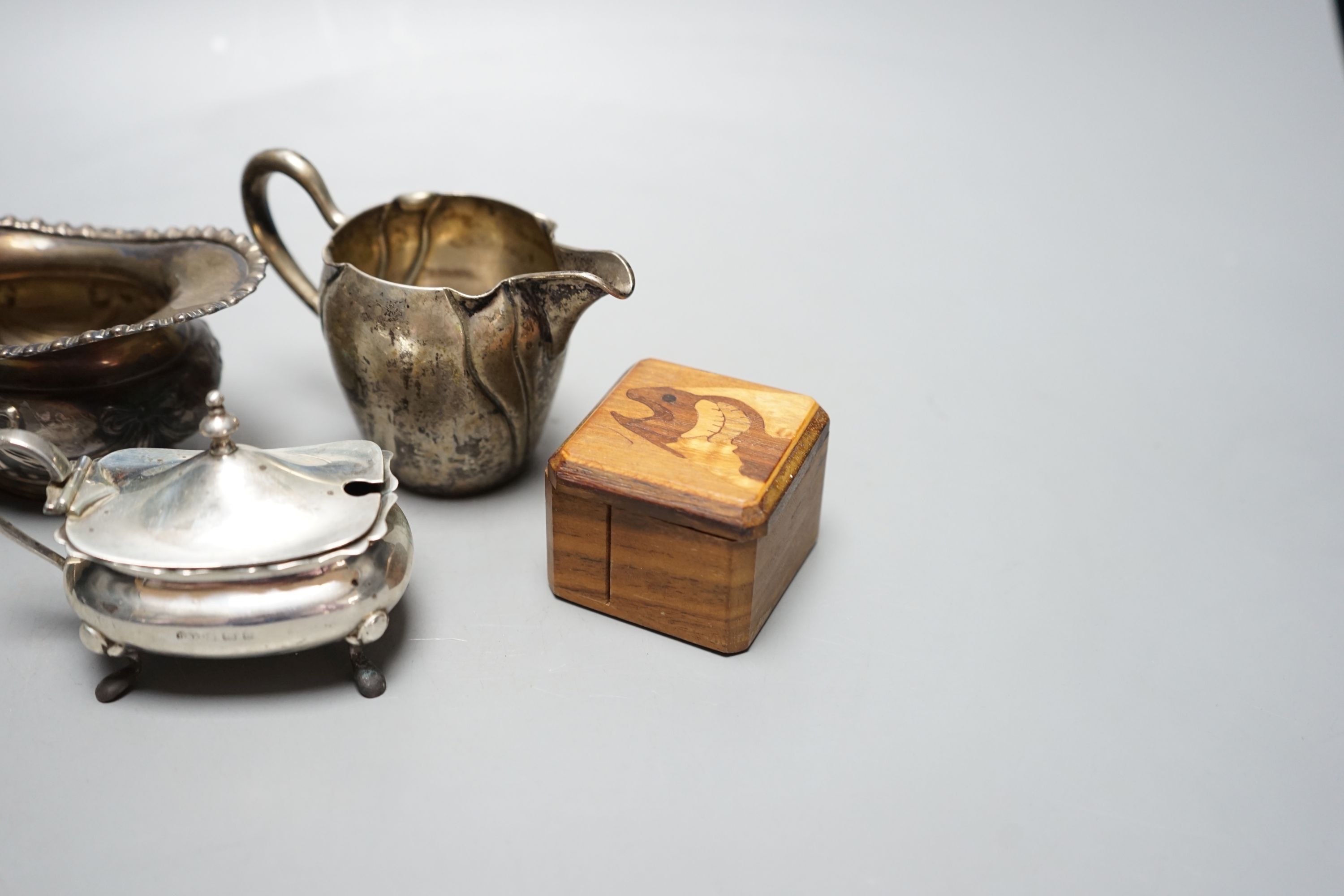 A late Victorian silver cream jug, London, 1900, a German 800 cream jug, a silver mustard pot, two silver napkin rings, a silver lid and a wooden box